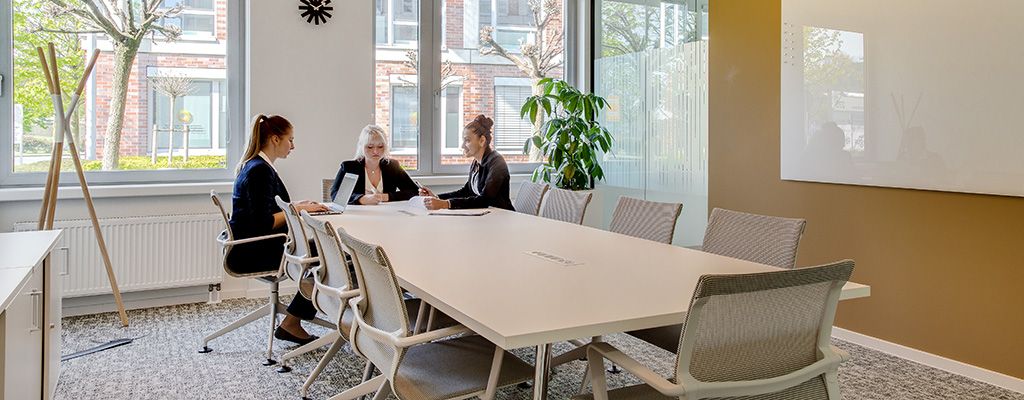Three businesswomen sat around a large meeting table